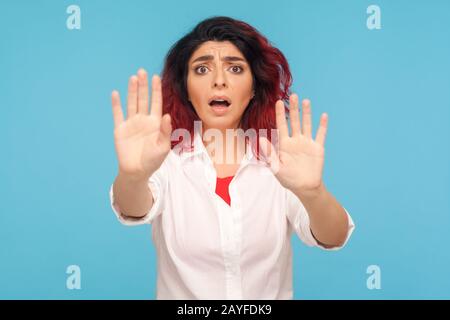 No, temo! Ritratto di donna spaventata con capelli rossi fantasia in camicia bianca gesturante stop e gridare dalla paura, paura di minaccia improvvisa. Io Foto Stock