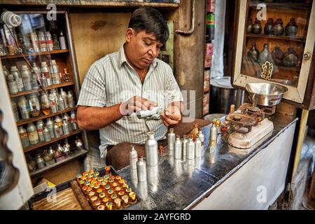 Uomo nel negozio di profumi che mescola fragranze, colorato streetlife sul mercato di Jodhpur, Rajasthan, India Foto Stock