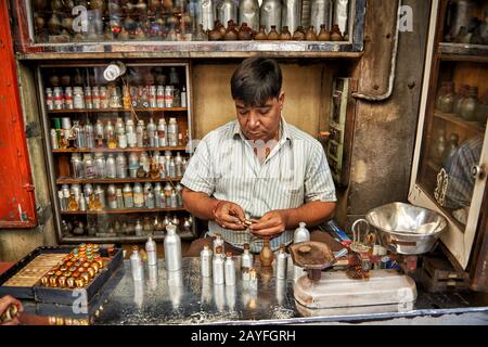 Uomo nel negozio di profumi che mescola fragranze, colorato streetlife sul mercato di Jodhpur, Rajasthan, India Foto Stock