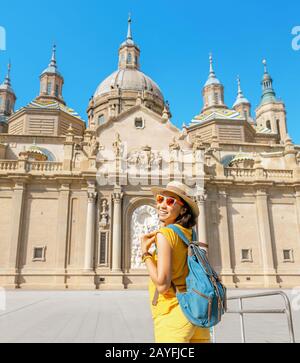 Giovane felice donna turistica a piedi vicino alla famosa cattedrale del Pilar sulla piazza centrale durante le vacanze estive a Saragozza città, Aragona, Spagna Foto Stock