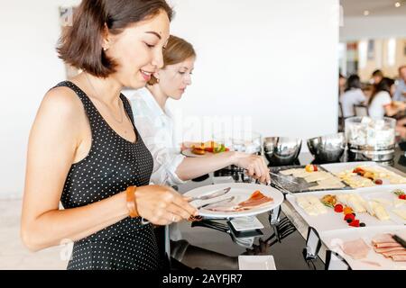 Donna che raccoglie cibo a tutti si può mangiare a buffet a colazione in hotel Foto Stock