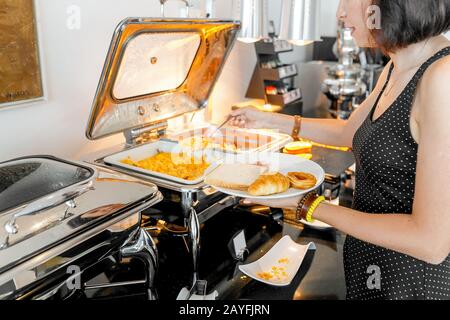 Donna che raccoglie cibo a tutti si può mangiare a buffet a colazione in hotel Foto Stock