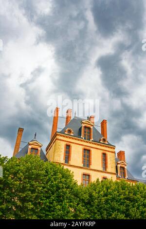 Vista dell'edificio Cour des Offices, parte dello Chateau de Fontainebleau (Palazzo di Fontainebleau), sotto un cielo nuvoloso. Seine-Et-Marne, Francia. Foto Stock