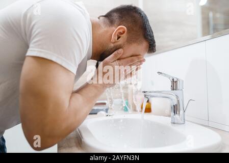 L'uomo lava il viso in bagno, igiene del mattino Foto Stock