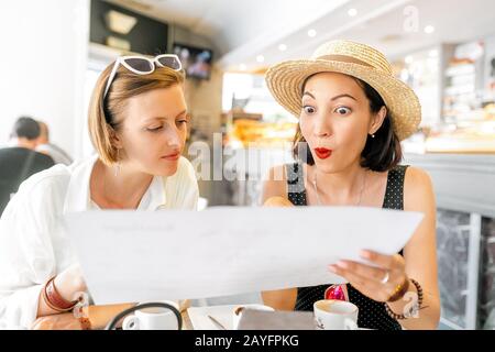 La ragazza, rimasta scioccata e sorpresa, guarda il menu del ristorante Foto Stock