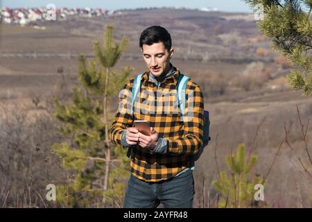 primavera all'aperto. bell'uomo in campagna con il telefono per navigare Foto Stock
