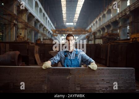 Lavoratore maschile a pila di pezzi metallici Foto Stock