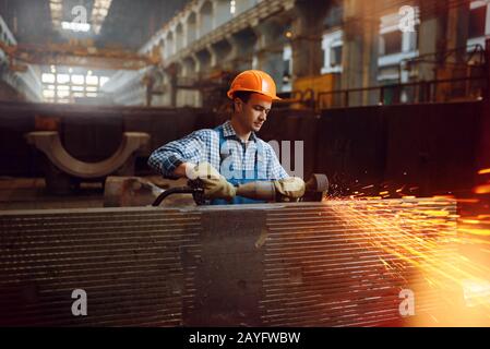 Il lavoratore in casco lavora con pezzi metallici Foto Stock