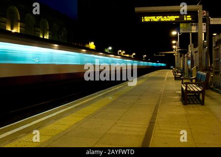 Immagine notturna di un treno sotterraneo che supera una piattaforma a Londra Foto Stock