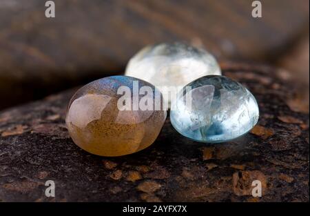 Pietre minerali di labradorite tagliate rotonde con fondo di pietre scure. Foto Stock