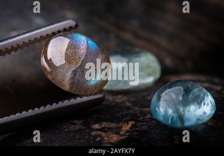 Pietre minerali di labradorite tagliate rotonde con fondo di pietre scure. Foto Stock