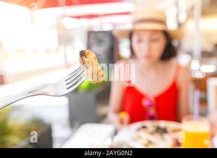 Donna che mangia cozze di molluschi nel ristorante di pesce Foto Stock