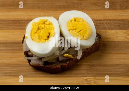 Panino con aringhe, cipolle e uova di pollo su un vassoio di legno cucina nazionale russa Foto Stock