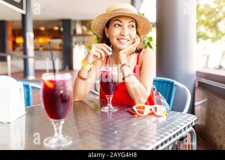 Giovane donna asiatica che beve sangria, tradizionale spagnolo tipo di vino da frutta in ristorante all'aperto Foto Stock