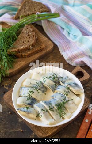 Cucina mediterranea. Frutti Di Mare. Gustoso sgombro appetitoso sottacolato in salsa con spezie su un tavolo di legno rustico scuro. Foto Stock