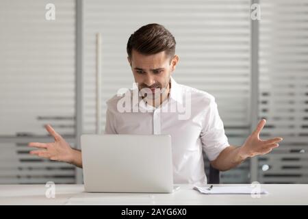 Lavoratore maschile confuso che ha problemi di notebook in ufficio Foto Stock