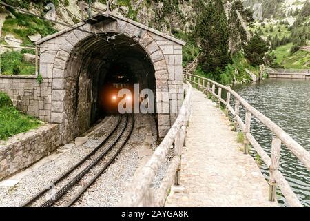 Il treno lascia il tunnel in montagna Foto Stock