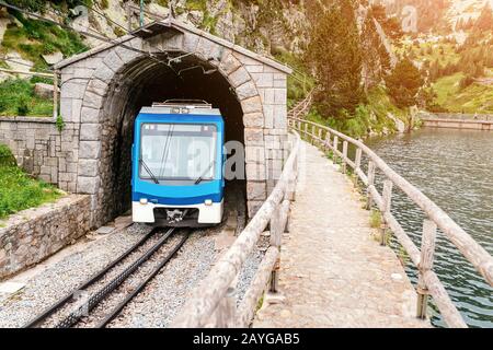 Il treno lascia il tunnel in montagna Foto Stock