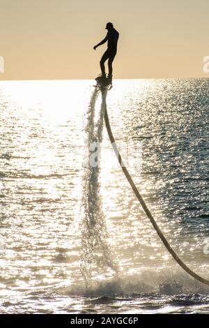 Volare a bordo di sport acquatici estremi a Ras al Khaimah, Emirati Arabi Uniti vicino a Dubai al tramonto divertirsi sull'acqua. Concetti sportivi e ricreativi Foto Stock