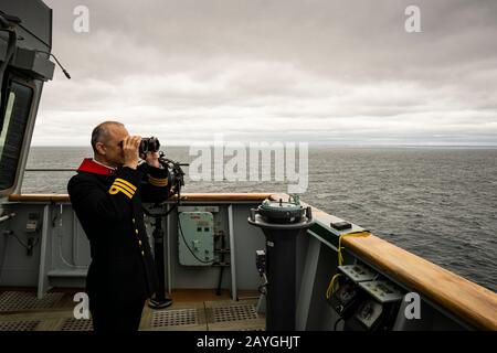 Il Comandante Philip Harper scandisce l'orizzonte dal ponte della REGINA ELISABETTA della HMS al mare al largo di Halifax, Nuova Scozia, Canada. Foto Stock