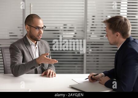 Il candidato maschio serio parla con il datore di lavoro all'intervista Foto Stock