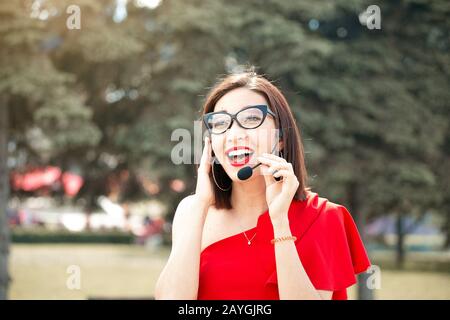 Donna asiatica con microfono vivavoce come pianificatore professionale di nozze Foto Stock