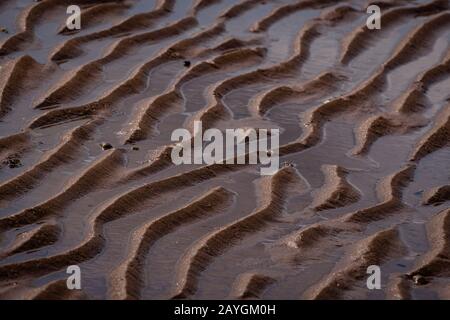L'azione dell'onda ha generato le increspature della sabbia su una spiaggia. Foto Stock