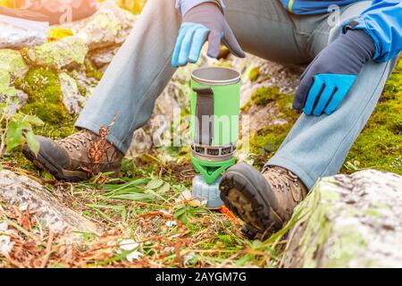 Uomo escursionista prepara cibo su un bruciatore a gas vicino al campo turistico Foto Stock