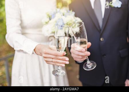 Sposo e sposa Brindisi e bicchieri di graffatura al partito di nozze Foto Stock