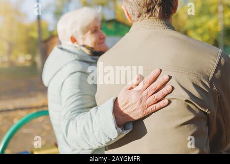 Anziani senior coppia innamorata di riposare su una panchina nel parco autunnale Foto Stock