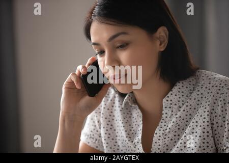 Giovane donna pensiva impegnata a parlare al cellulare Foto Stock