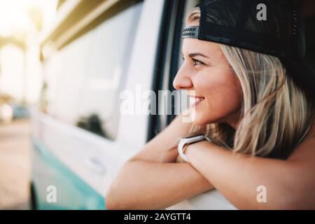 Giovane donna sorridente guarda fuori la finestra del furgone Foto Stock