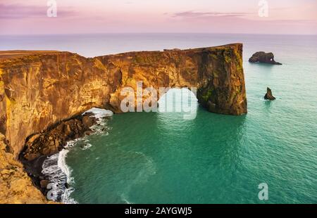 Arco di lava naturale nel mare. Capo Dyrholaey, costa dell'Islanda. Popolare attrazione turistica. Mondo di bellezza. Foto Stock