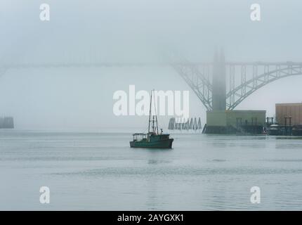 Una barca da pesca arriva dal mare in una giornata nebbiosa a Newport, Oregon Foto Stock