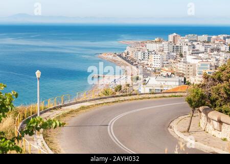 Strada tortuosa e città resort Rodi e baia di mare azzurro Foto Stock