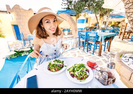 Giovane ragazza elegante nel ristorante insalata condimento con olio d'oliva. Concetto di cucina greca e verdure fresche Foto Stock