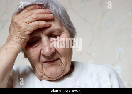 La donna anziana ha messo la sua mano sulla fronte. Donna con capelli grigi, concetto di mal di testa, pressione e età avanzata Foto Stock