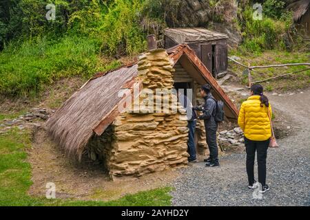 Turisti a 19th capanna secolo a villaggio insediamento cinese, costruito da immigrati, minatori d'oro, a Arrowtown, Otago Regione, Isola del Sud, Nuova Zelanda Foto Stock