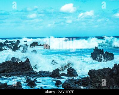 Blolole di lava nelle Hawaii. L'oceano erode la piattaforma di lava sott'acqua e poi soffia attraverso i fori nella parte superiore. Foto Stock