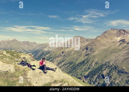 Giovane hiker femminile che riposa su una roccia che progetta la sua prossima mossa. Foto Stock