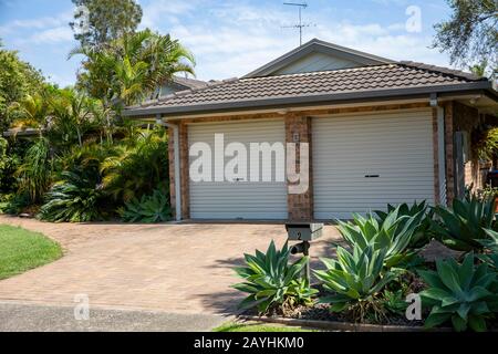 Casa australiana e giardino con doppio garage piante e erba nel sobborgo di Sydney di Mona vale, nuovo Galles del Sud, Australia Foto Stock