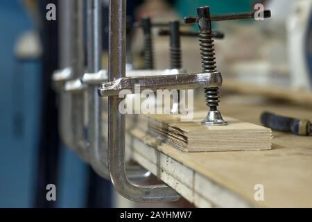Pezzi di legno serrati che si collegano con morsetto speciale, pezzi di legno nell'officina di carpenteria Foto Stock