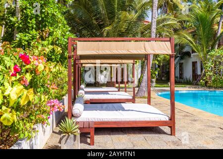 Tangalle, Sri Lanka - 4 novembre 2017: Letti in spiaggia in un hotel tropicale. Piscina con acqua blu nei tropici. Splendido resort idilliaco tra le palme Foto Stock