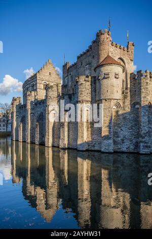 Gravensteen Castello e la sua riflessione sul canale in una splendida giornata di cielo blu, Gand Foto Stock
