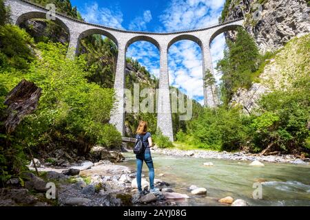 Viadotto Landwasser A Filisur, Svizzera. Giovane donna guarda la famosa attrazione turistica. Panorama panoramico dell'alto ponte ferroviario in montagna. A. Foto Stock