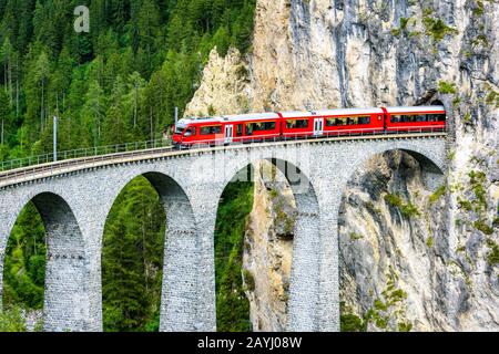 Viadotto Landwasser A Filisur, Svizzera. E' un famoso punto di riferimento delle Alpi Svizzere. Il treno Red Express parte dal tunnel di montagna sul ponte alto. Panoramica Foto Stock