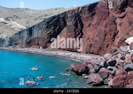 Akrotiri, Grecia - 19 luglio 2019: Nuotatori e bagnanti che si godono il sole sulla Spiaggia Rossa Foto Stock