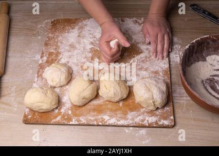 Una donna inginocchia l'impasto. Tagliere compensato, setaccio di farina di  legno e spina di laminazione di legno - attrezzi per fare l'impasto Foto  stock - Alamy