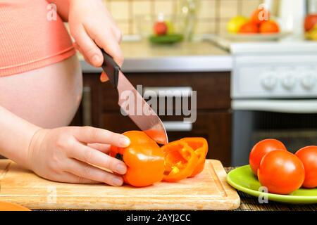 Donna incinta che prepara un pasto sano in cucina Foto Stock