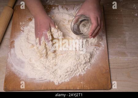 Una donna inginocchia l'impasto. Tagliere compensato, setaccio di farina di  legno e spina di laminazione di legno - attrezzi per fare l'impasto Foto  stock - Alamy